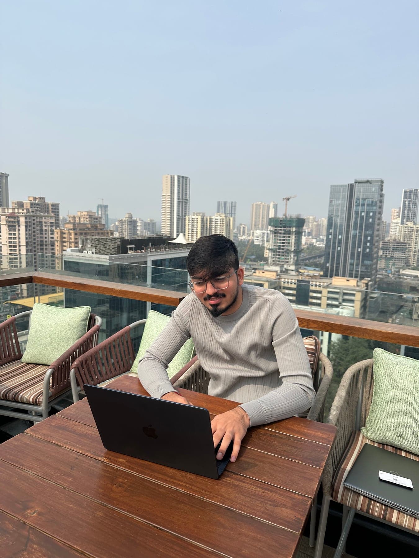 Utsav Somaiya working on a laptop at a rooftop table overlooking the city